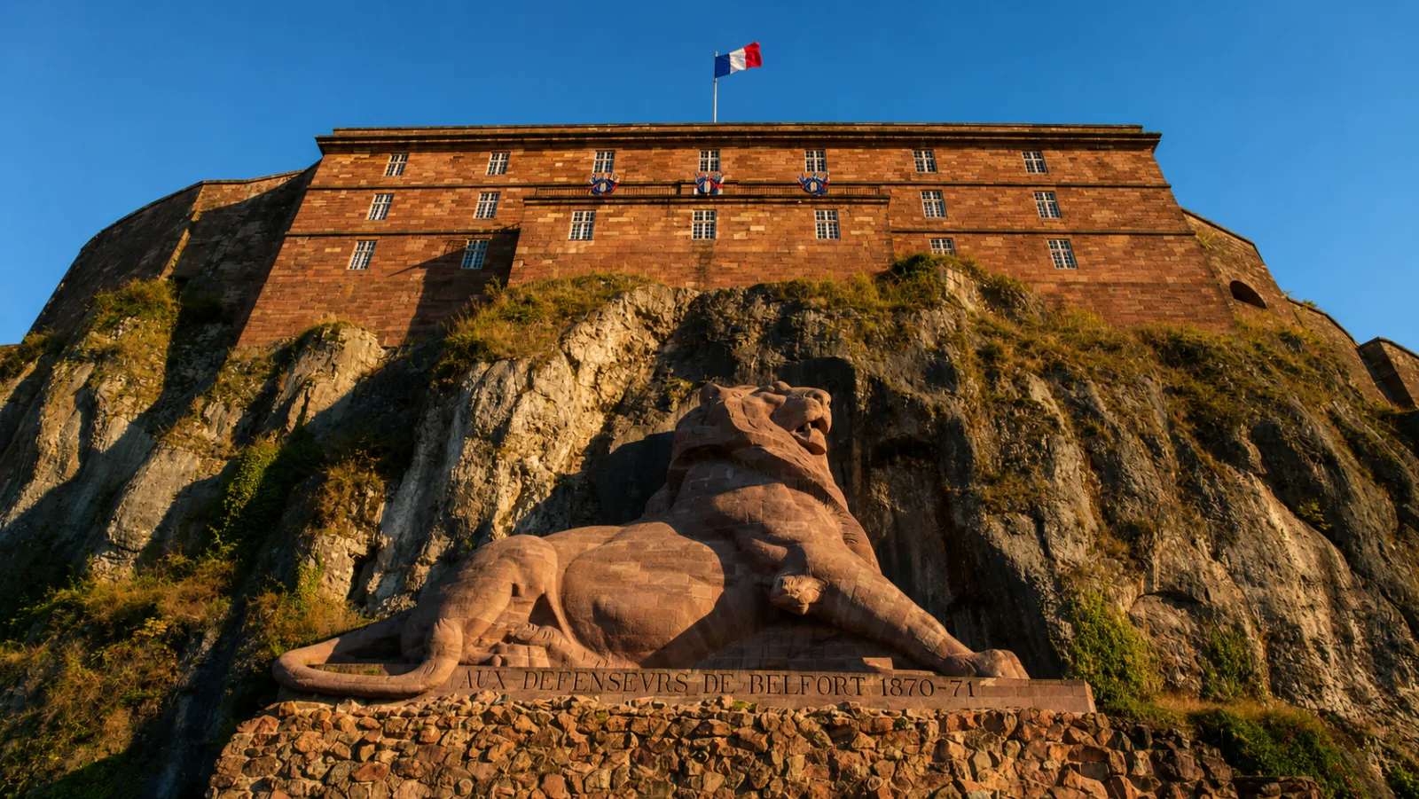 Le Lion de Bartholdi au pied de la citadelle de Belfort — un monument taillé dans le grès, adossé au rocher qui porte la forteresse
