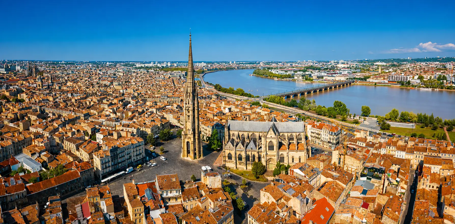 Vue aérienne de Bordeaux — la flèche Saint-Michel, la Garonne et le pont de pierre : un centre ancien dense bâti sur les alluvions de la rive gauche