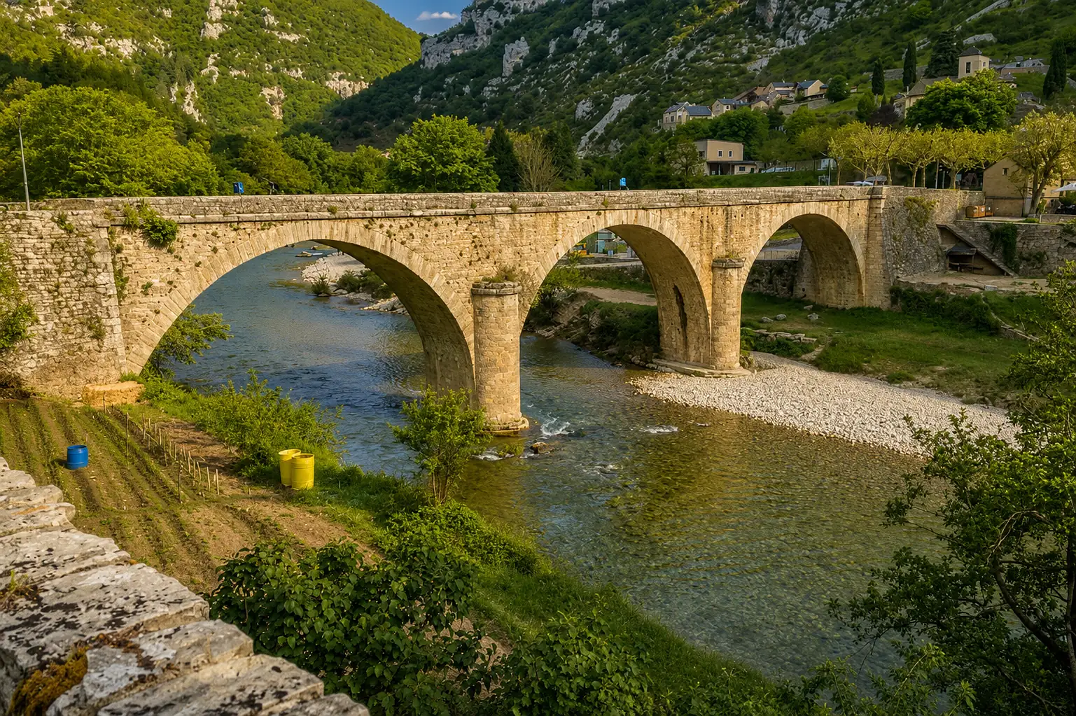 Un pont de pierre à trois arches sur une rivière encaissée de Lozère — piles plantées dans un lit de galets, au pied de versants calcaires