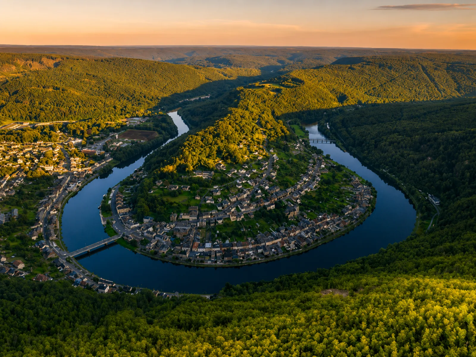 La Meuse enlaçant un promontoire boisé — méandre encaissé du val de Meuse, la ville étagée entre fleuve et forêts