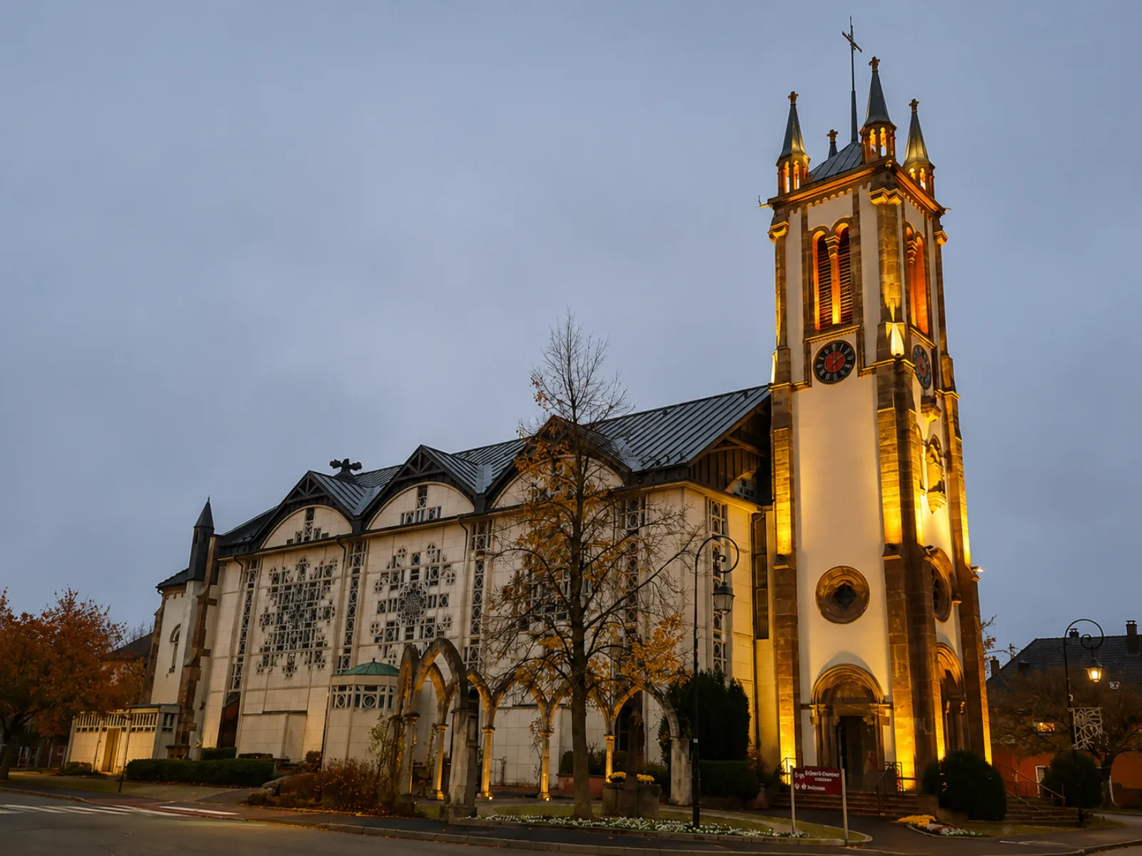 L'église de Rixheim illuminée au crépuscule — tour de grès et nef claire au cœur du bourg, à l'est de Mulhouse