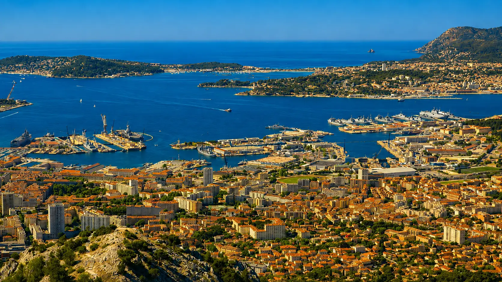 La rade de Toulon vue du mont Faron — l'arsenal au bord de l'eau, la ville au pied de reliefs dont le tunnel a dû démêler neuf familles de terrains