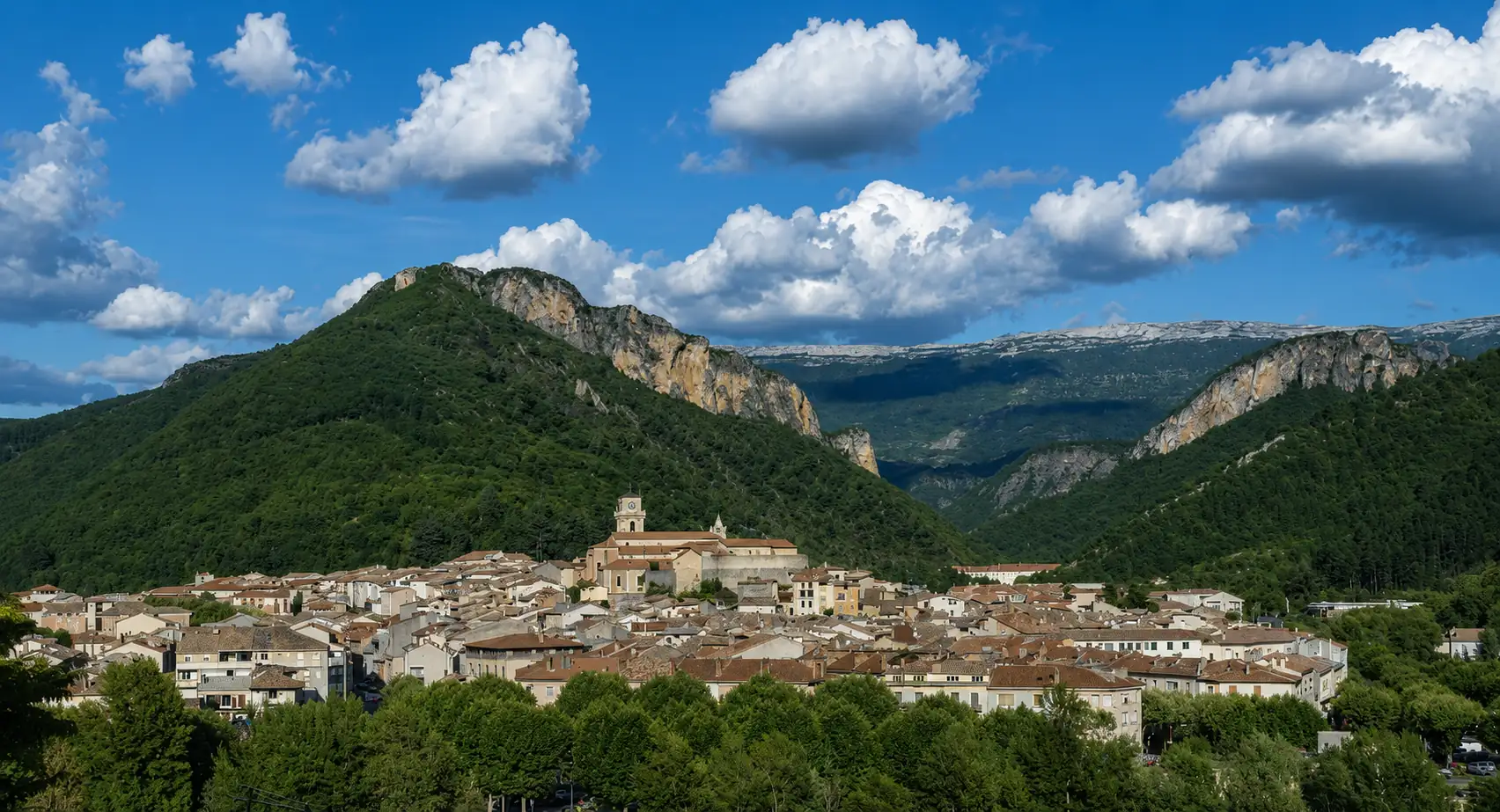 Un bourg de Haute-Provence serré au pied des barres calcaires, gorges en arrière-plan — bâtir ici, c'est composer avec le relief et la roche